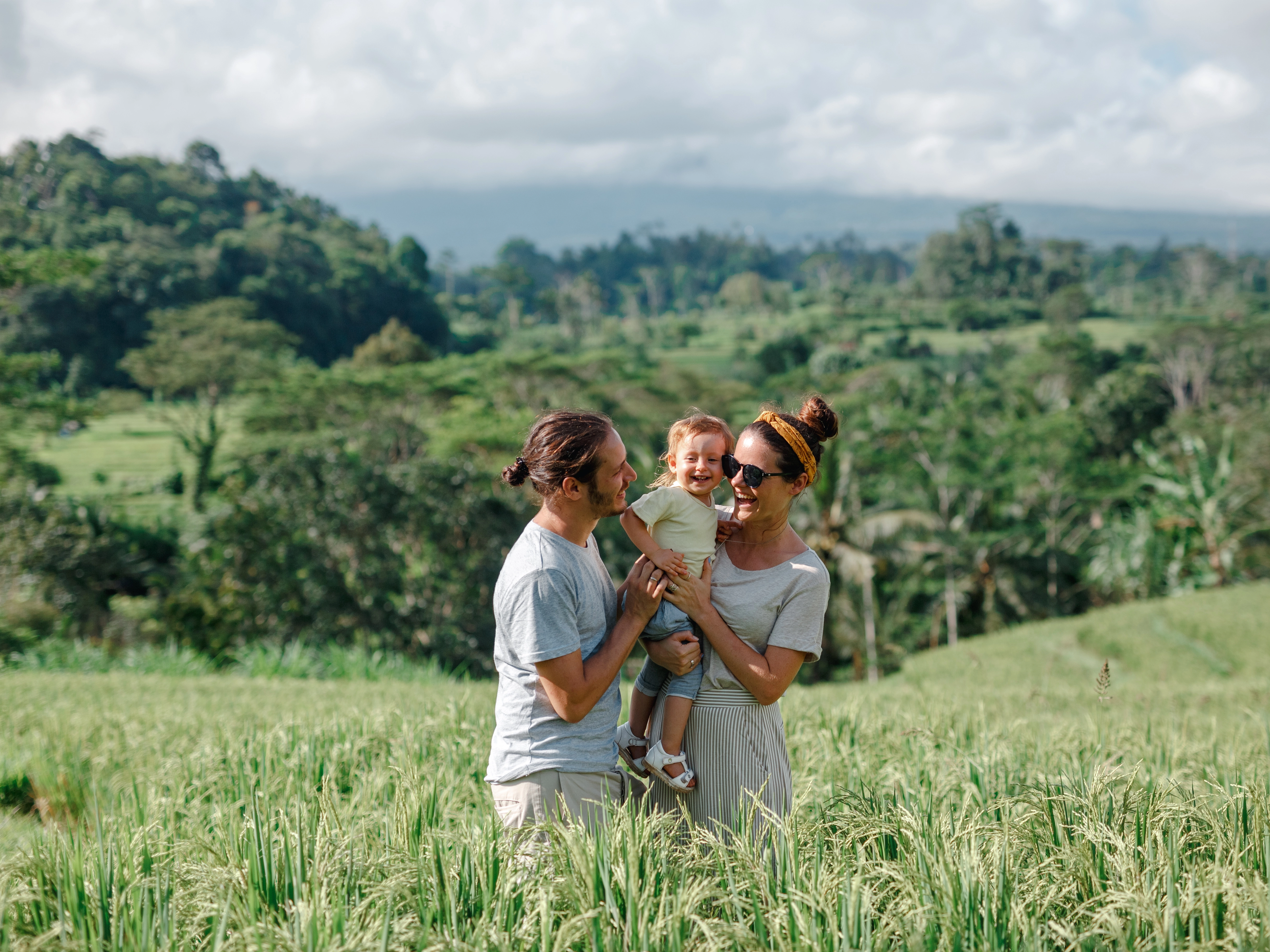 Happy mother, father and baby in high green grass